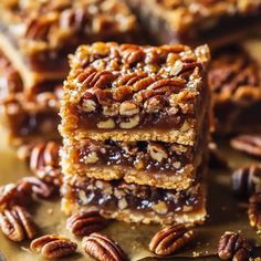 several pieces of pecan bar stacked on top of each other with nuts around them