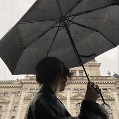 a woman holding an umbrella in front of a building