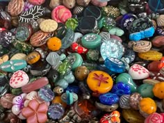 there are many different colored beads in this pile, including one with a bow on it