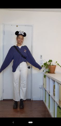 a woman wearing a pirate costume standing in front of a white door with her arms spread out