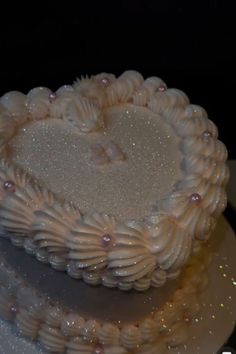 a heart shaped cake on a plate with some frosting and beads around the edges