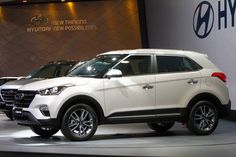 two white suvs are on display at an auto show in front of a large sign