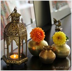 three vases with flowers and candles on a table