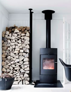 a fire place sitting next to a pile of logs in a room with white walls