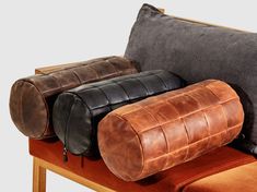 three different colored pillows sitting on top of a brown couch next to a black pillow