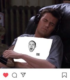 a man laying on top of a chair holding a paper with an image of a face