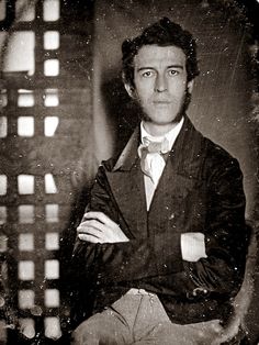 an old black and white photo of a man in a suit with his arms crossed