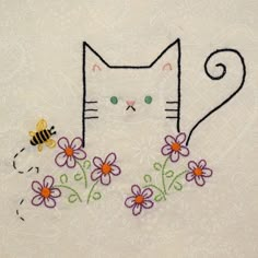 a white cat with flowers and a bee embroidered on it's back, sitting in front of a floral design