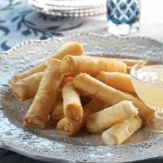 some food on a silver plate with a small bowl of dipping sauce in the middle