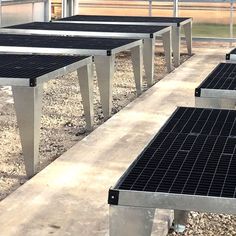 four metal benches sitting on top of a gravel field