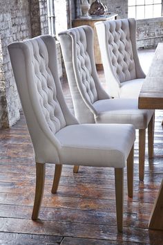 a set of four upholstered chairs sitting on top of a wooden floor