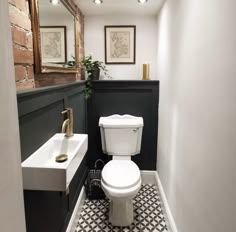 a white toilet sitting next to a sink in a bathroom under a mirror on the wall