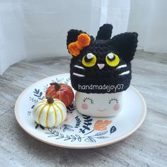 a black cat hat sitting on top of a white plate next to an orange pumpkin