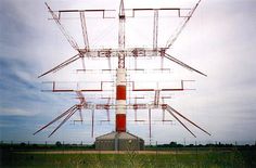 a tall tower sitting in the middle of a green field with power lines above it