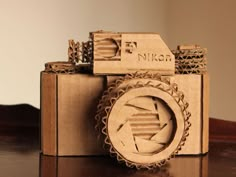 a wooden camera sitting on top of a table next to a bottle opener with the word nikon printed on it