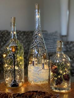 three wine bottles with lights in them sitting on a table next to a piece of wood