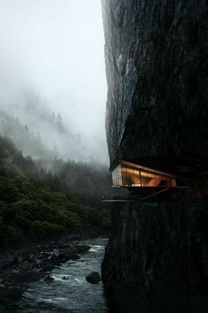 a house built into the side of a cliff next to a river