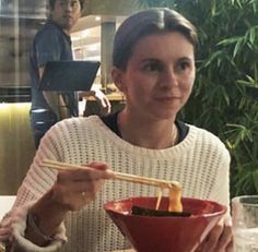 a woman sitting at a table with chopsticks in her hand