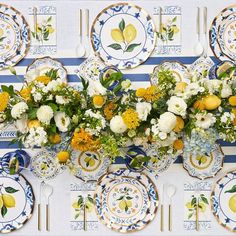 a table topped with plates covered in yellow and white flowers next to blue striped wall