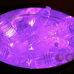 there are many empty water bottles in the bowl with purple light on it's side