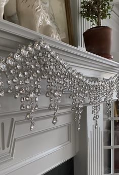 a white fireplace with crystal beads hanging from it's mantle