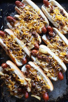 several hot dogs covered in cheese and chili