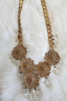 "This is a vintage 1920s-1930s statement necklace. The gold tone metalwork is very intricate and is in a round filigree design. There is one visible area of tarnish (pictured) from wear and age. The necklace has a unique chain and crystal tone details. All of the crystal tone gems are in excellent condition. Overall this necklace is in great condition. Measurements: Length: 9.5\" | Length of detail: 2.5\" Unless otherwise stated all vintage items are used and may have minor to moderate wear or d Vintage Gold-tone Metal Jewelry, Vintage Gold Metal Jewelry, Ornate Brass Jewelry With Vintage Charm, Elegant Metal Necklaces With Antique Finish, Elegant Metal Necklace With Antique Finish, Art Deco Gold Jewelry With Intricate Design, Gold Art Deco Jewelry With Intricate Design, Elegant Bronze Necklaces With Intricate Design, Elegant Bronze Necklace With Intricate Design