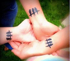 two people with tattoos on their hands holding each other's hand and the words three little birds above them