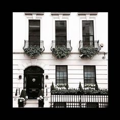 a white building with black iron railings and flower boxes on the front door is shown