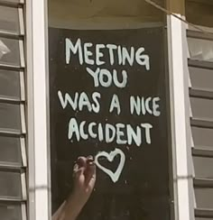 a hand writing on a window sill that says meeting you was a nice accident