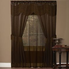 a living room filled with furniture and a window covered in brown curtaining next to a table