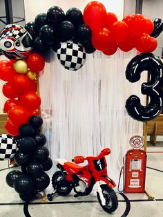 a motorcycle and some balloons are on display in front of a number three balloon arch