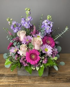 a vase filled with purple flowers on top of a wooden table