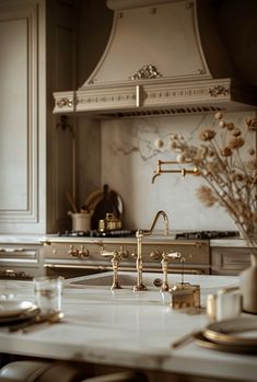 a white kitchen with gold accents and marble counter tops