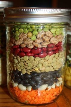 a jar filled with lots of different types of beans and nuts on top of a wooden table