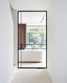 a white couch sitting in the middle of a room next to a glass wall with sliding doors