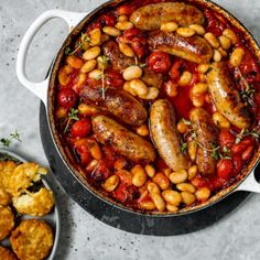 sausages and beans are in a pan with other food items on the table next to them