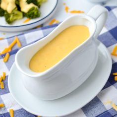 a white bowl filled with soup sitting on top of a plate next to broccoli