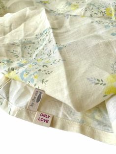 the fabric is white with yellow flowers on it and has a tag that says only love