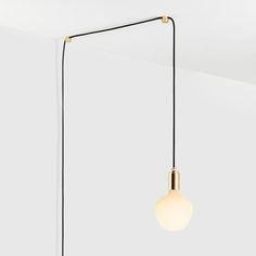 a black and gold lamp hanging from a ceiling in an empty room with white walls