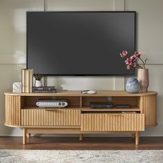 an entertainment center with a flat screen tv mounted on it's wall and two vases filled with flowers