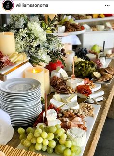 a table topped with lots of food and plates covered in cheese, crackers and grapes