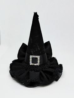 Miniature witch hat for babies, girls, adults and pets. Mini hat size is approximately 3.5 inches wide by 4 inches tall. Mini hat can be attached to a metal alligator clip, a soft elastic headband, or ribbon for pets. Please choose the finish: -2.6 inches alligator clip  -5/8 by 16 or 18 inches soft elastic headband  -3/8 by 18 or 25 inches ribbon (for pets) Finish color: -Metal Clip -Black  -Gray  -There may be slight variation in size  -Due to lighting color may vary slightly  -Miniature hats Halloween Costume Hat Accessories, Novelty Halloween Costume Hats And Headpieces As Gifts, Halloween Costume Hat, Witchy Brimmed Mini Hats For Halloween, Brimmed Mini Hats For Halloween Costume Party, Witchy Costume Hats And Headpieces For Party, Halloween Novelty Mini Hat With Curved Brim, Curved Brim Mini Hats For Halloween Costume Party, Halloween Novelty Mini Costume Hat