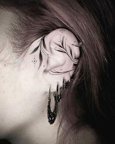 a woman's ear with black and white tattoos on her face, behind the ear