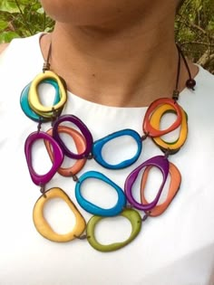 a woman wearing a necklace made out of multicolored circles on a brown cord