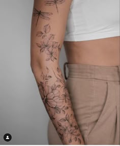 a woman's arm with flowers and dragonflies on it