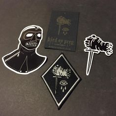 three different stickers on top of a table next to a patch with a knife