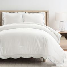 a white comforter with scalloped edges and blue piping on the bottom