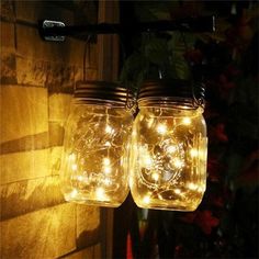 two mason jars with fairy lights hanging from them