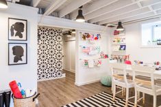 a white room with black and white decor on the walls, wood flooring and chairs